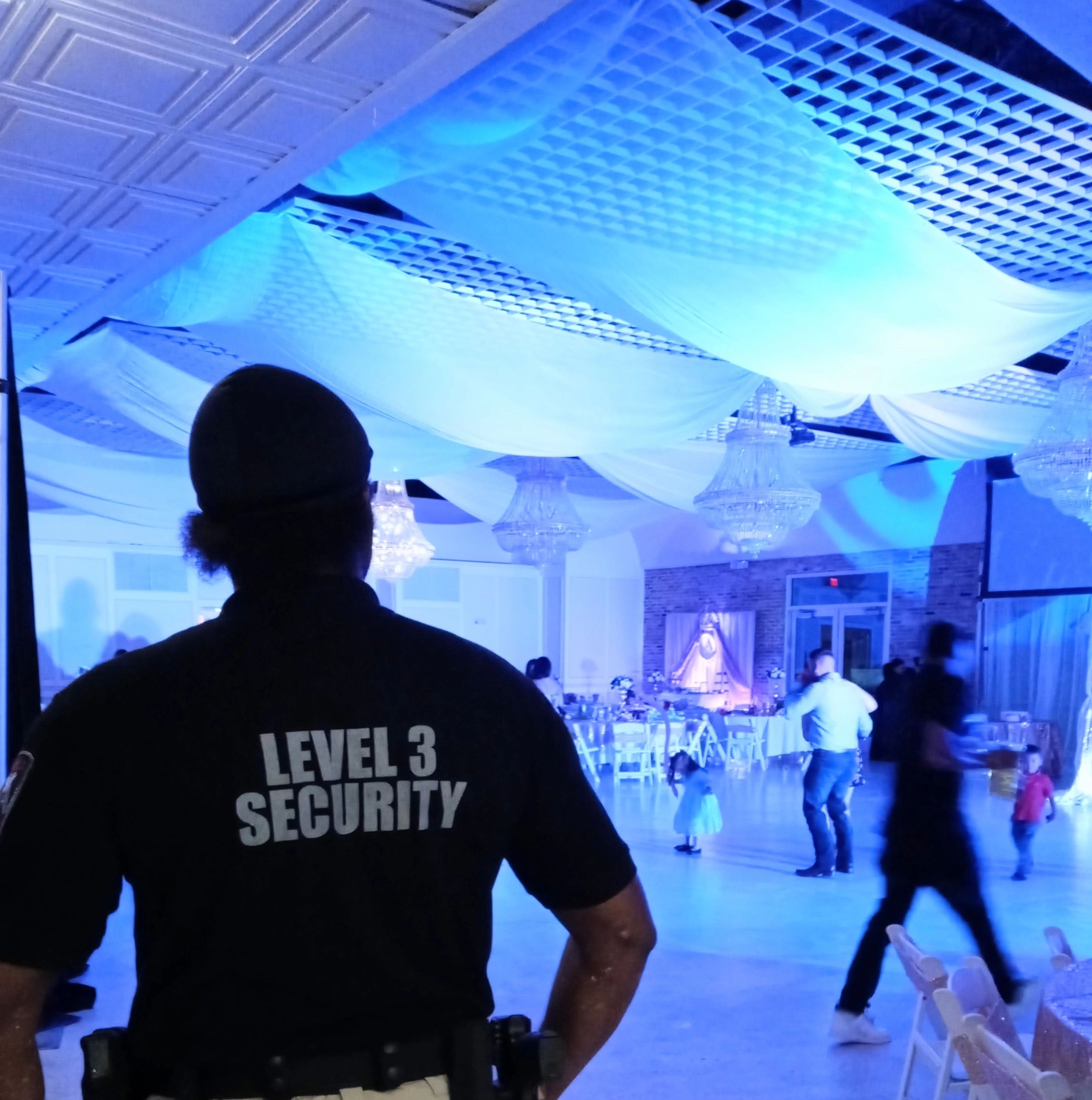 Level 3 Security guard monitoring indoor event with blue lighting